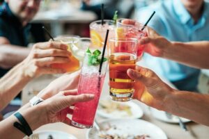 Pessoas à mesa a brindarem com copos de bebidas