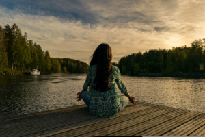 Mulher sentada à beira lago a meditar, meditação, lago, relaxamento